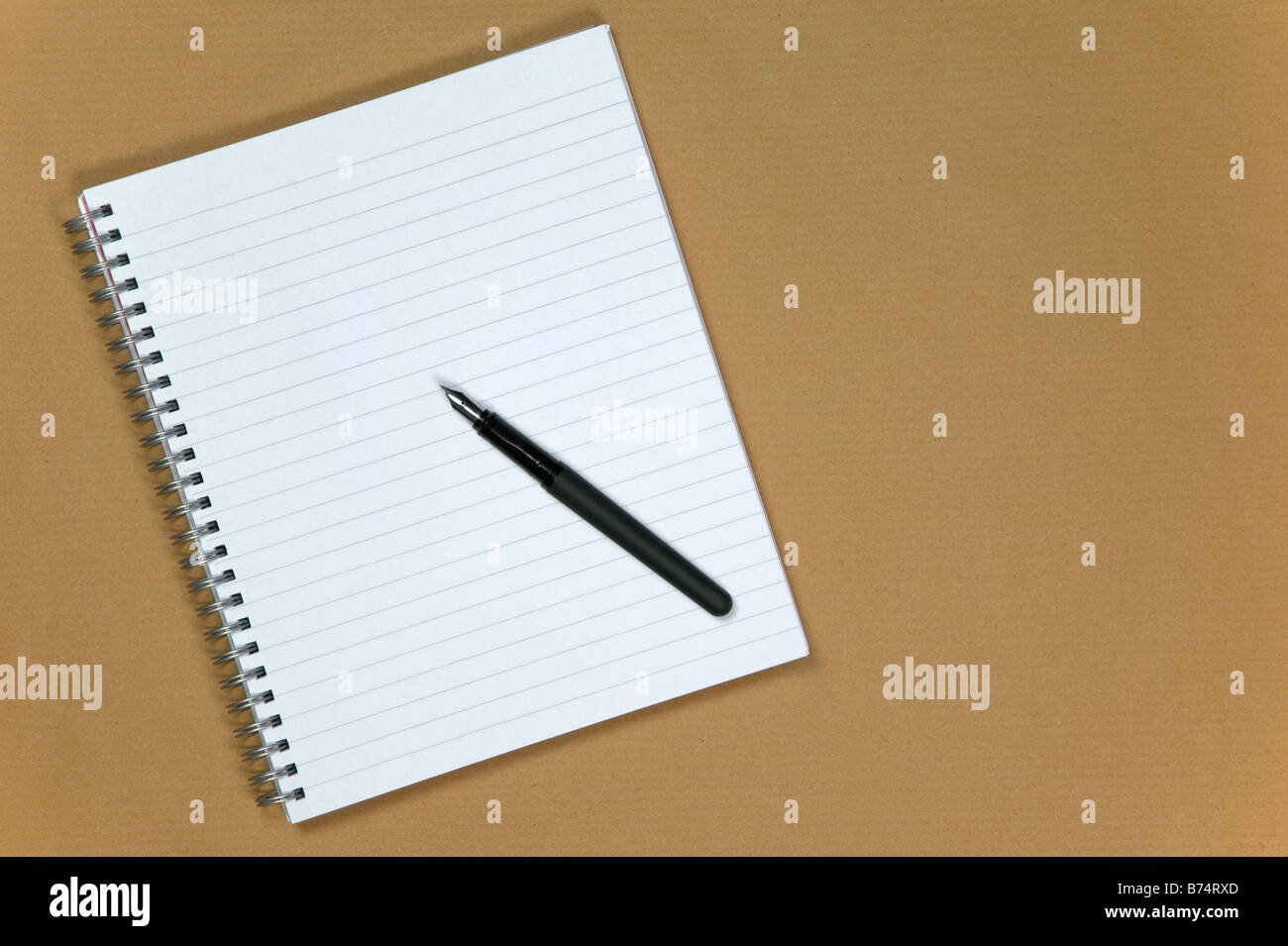 Notebook a spirale e penna stilografica su un marrone sfondo della carta Foto Stock