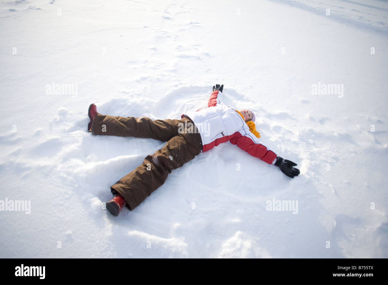 9 anno di età che giace sulla neve, rendendo angelo di neve, Winnipeg, Canada Foto Stock