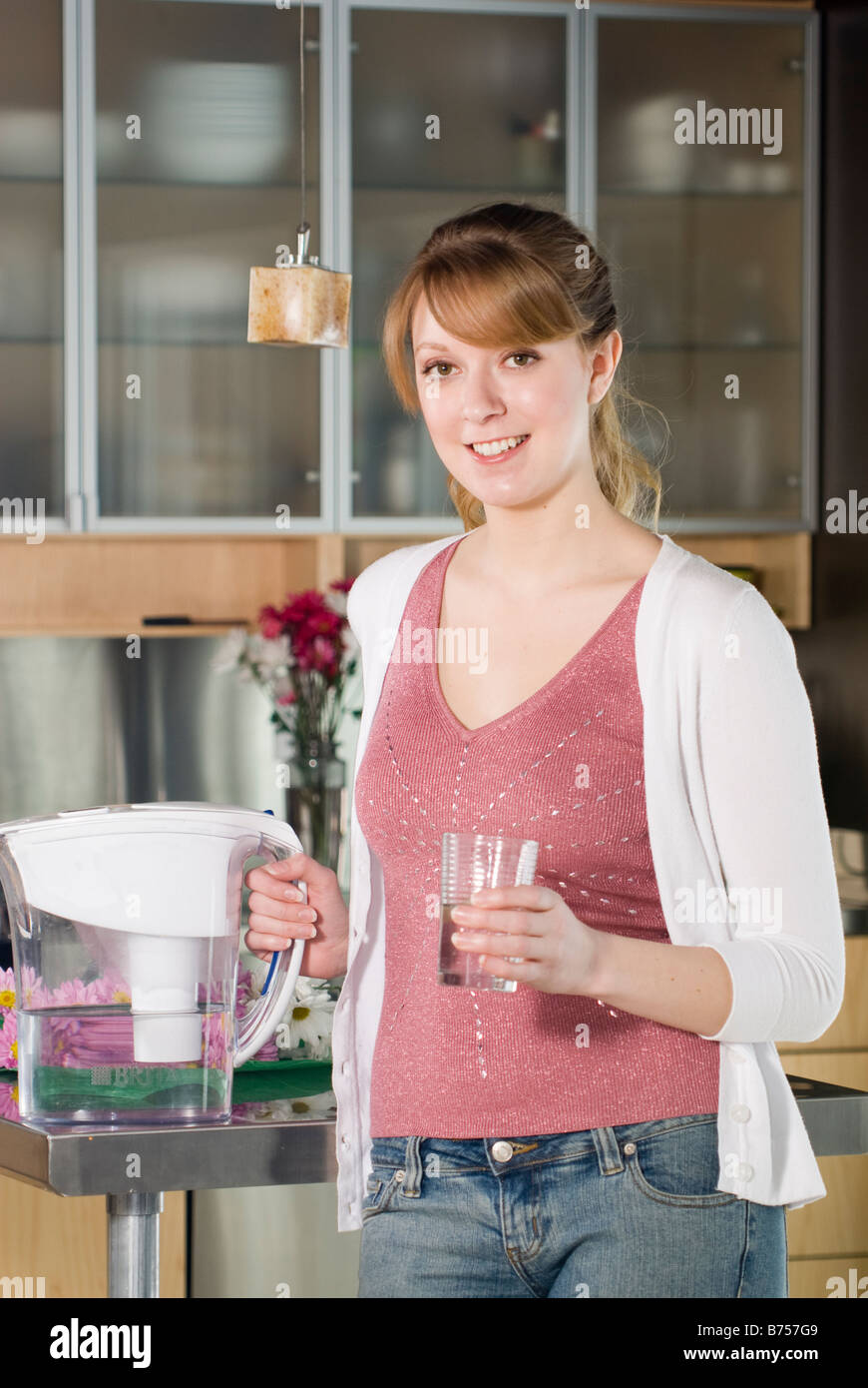 Donna con un bicchiere di acqua dalla brocca filtrato Foto Stock