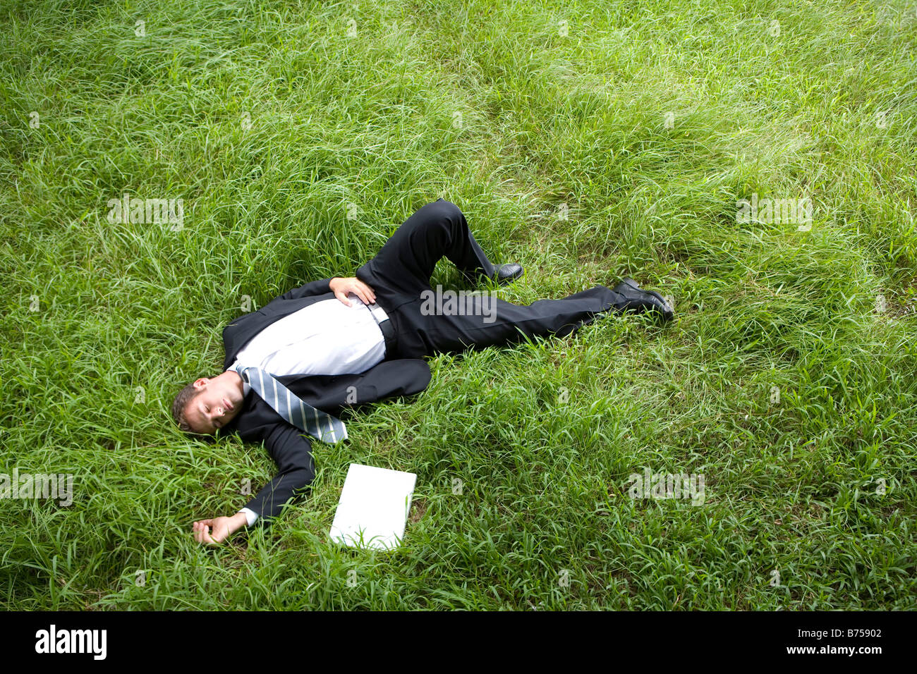 Una metà uomo adulto giacente sul prato del sonno da parte portatile Foto Stock