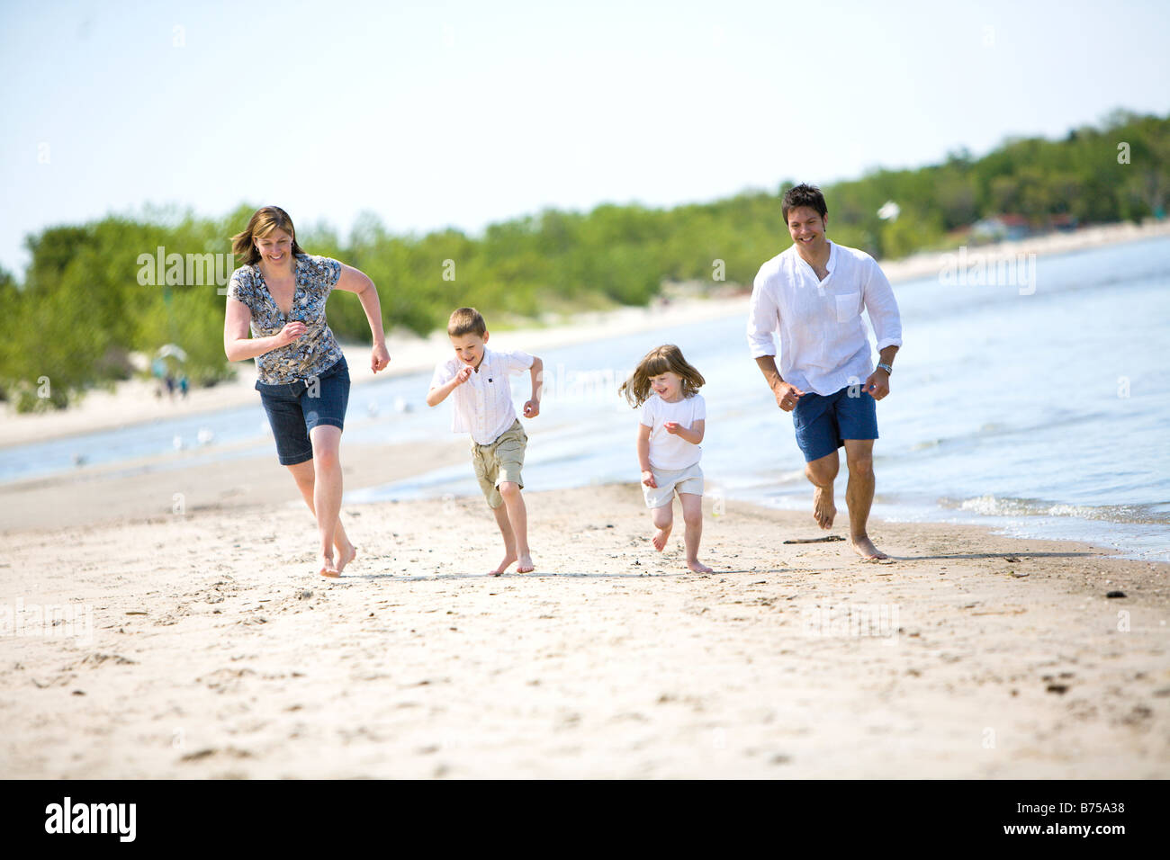 Famiglia di quattro persone in esecuzione lungo il litorale, Grand Beach Parco Provinciale, Manitoba, Canada Foto Stock