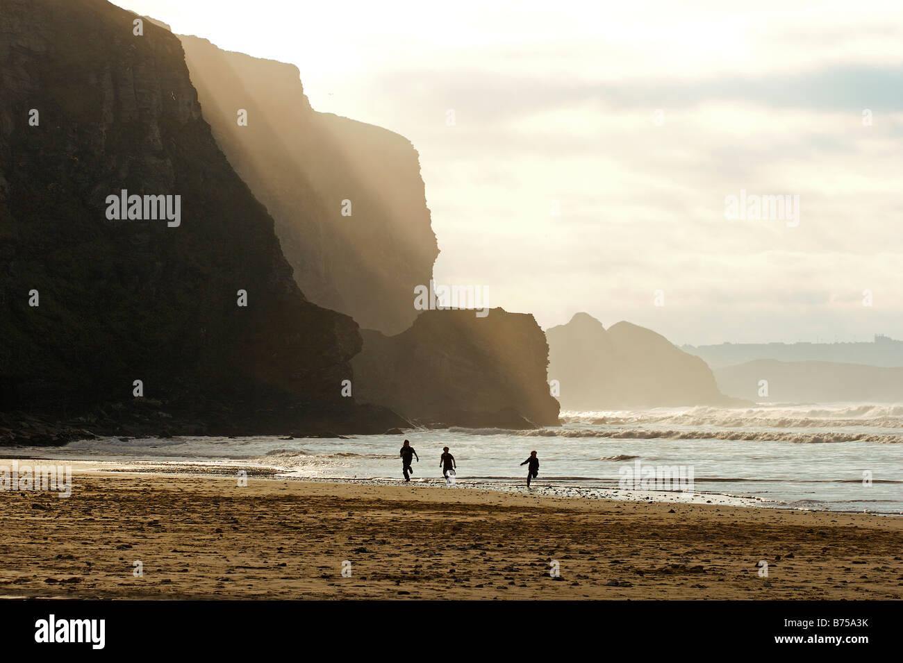 Ragazzi giocare sul bordo dell'acqua sulla spiaggia a Watergate Bay North Cornwall Foto Stock