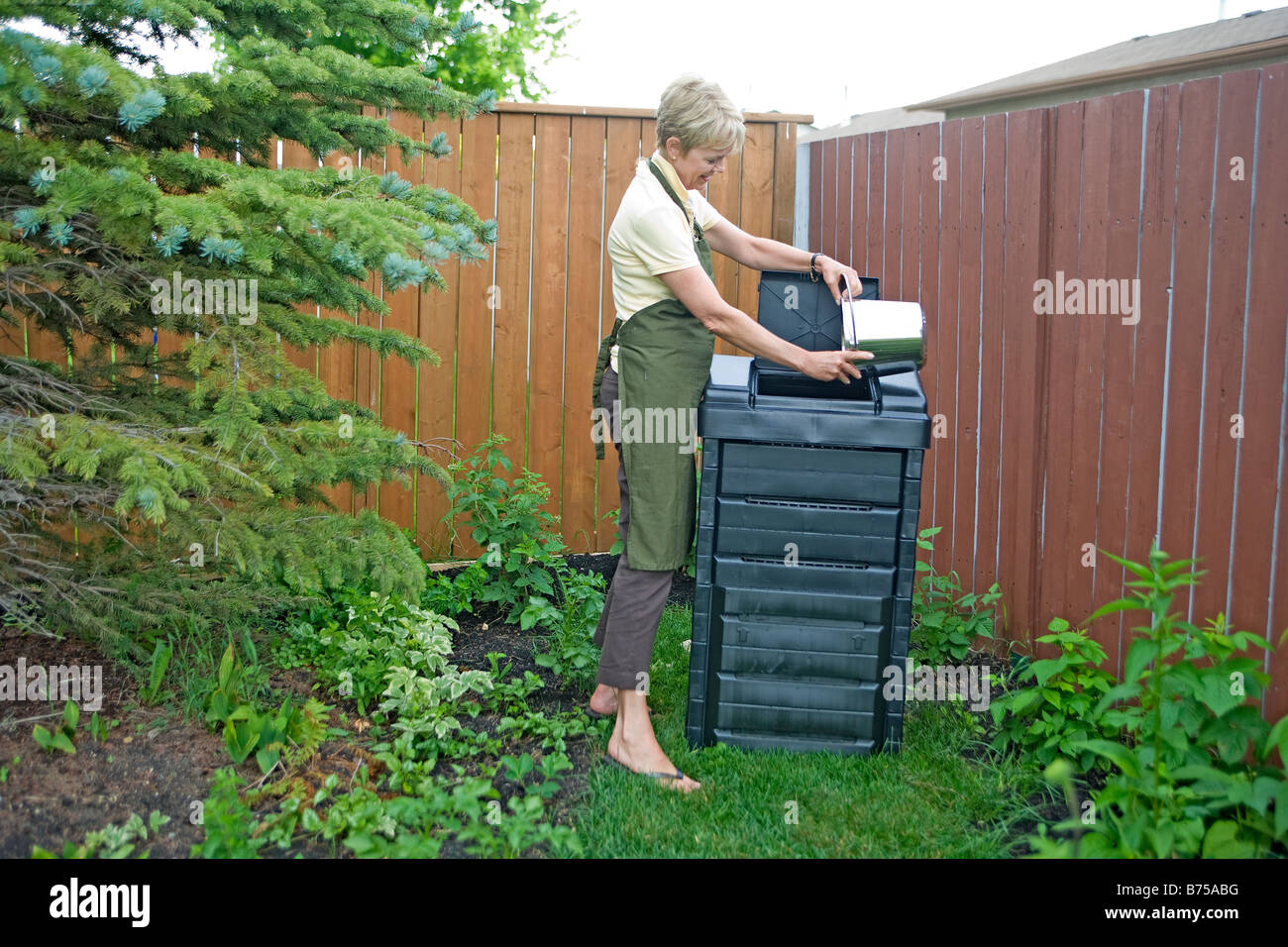 Senior donna si svuota scarti di cucina in compostiera, Winnipeg, Manitoba, Canada Foto Stock