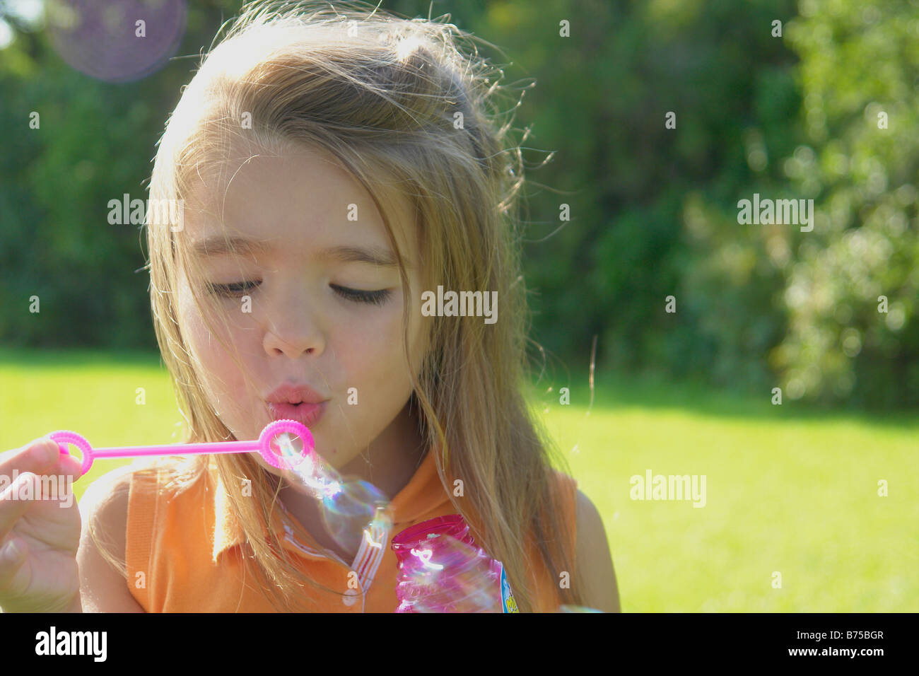6 anno vecchia ragazza soffiare bolle nel parco, Winnipeg, Canada Foto Stock
