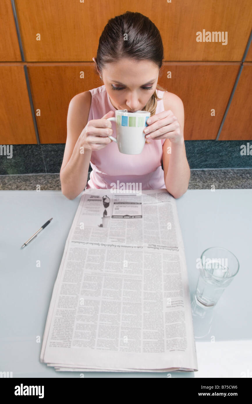 Angolo di alta vista di una imprenditrice di bere il caffè e la lettura di un quotidiano Foto Stock