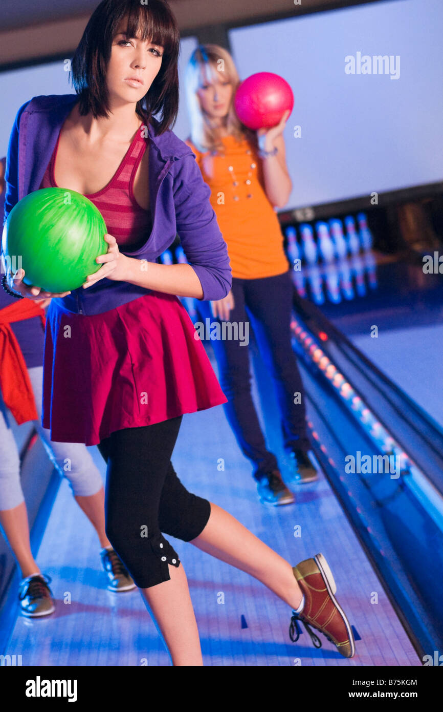 Ritratto di una giovane donna che gioca a dieci pin bowling con i suoi amici Foto Stock