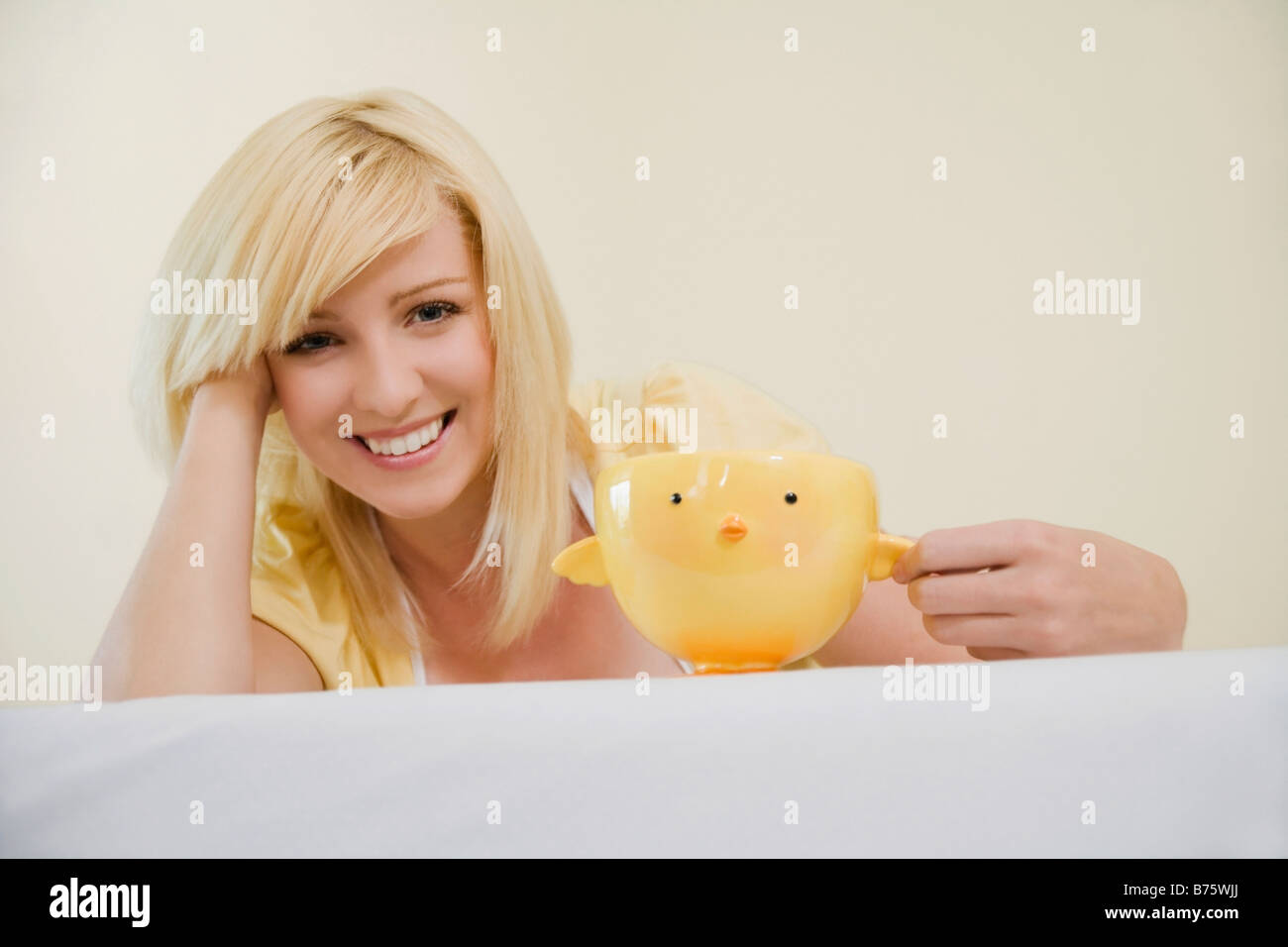 Ritratto di una giovane donna che mantiene una tazza e sorridente Foto Stock