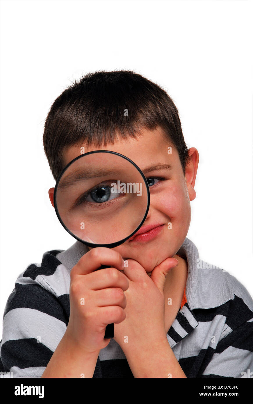 Un giovane ragazzo che guarda attraverso una lente di ingrandimento Foto Stock