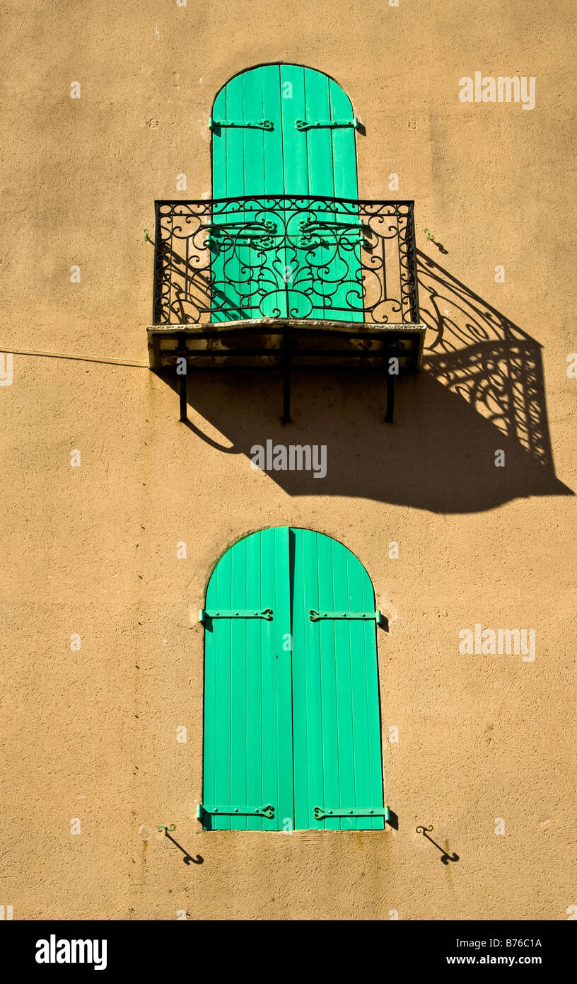 Persiane verdi e un balcone getta un' ombra su una parete gialla nella città di Collioure, Perpignan Foto Stock