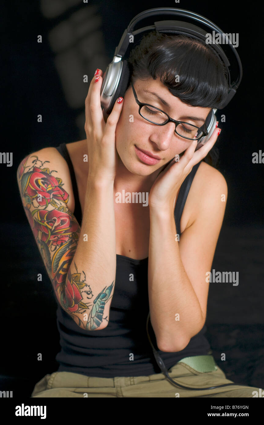 Emo ragazza con tatoo ascoltando musica sulle cuffie Foto Stock