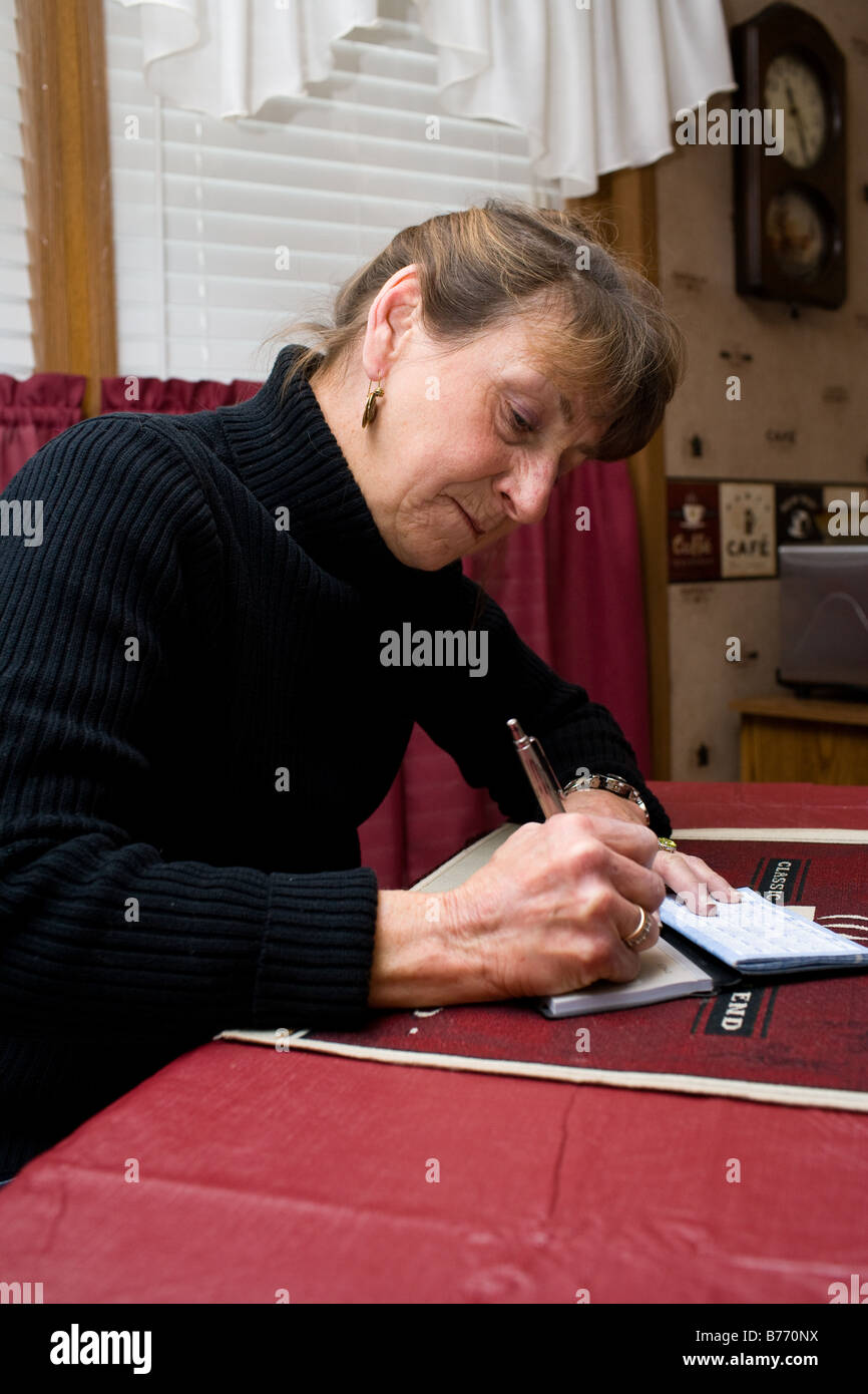 Una donna la scrittura di un controllo a pagare bollette mensili. Foto Stock