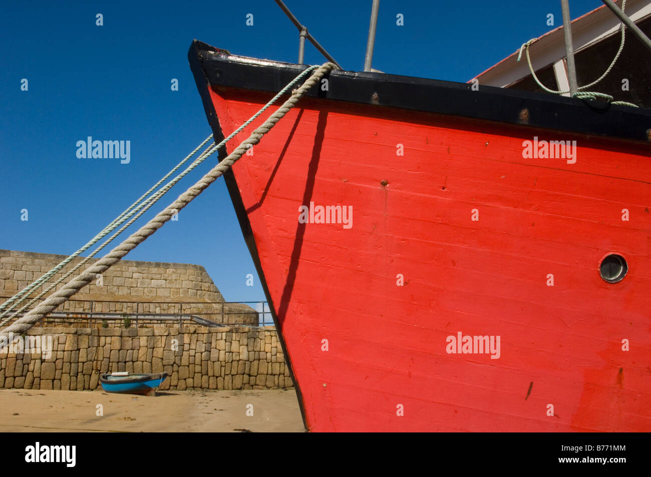 Un rosso barca ormeggiata presso la parete del porto con la bassa marea. Hugh Town. St Mary's. Isola di Scilly. In Inghilterra. Regno Unito Foto Stock