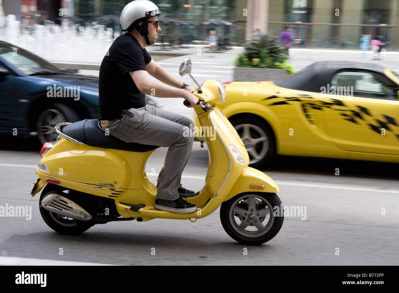 Un uomo su uno scooter giallo nel traffico Foto Stock