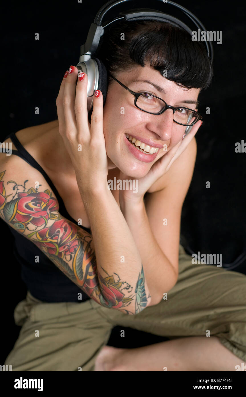Donna con tattoo ascoltando musica sulle cuffie Foto Stock