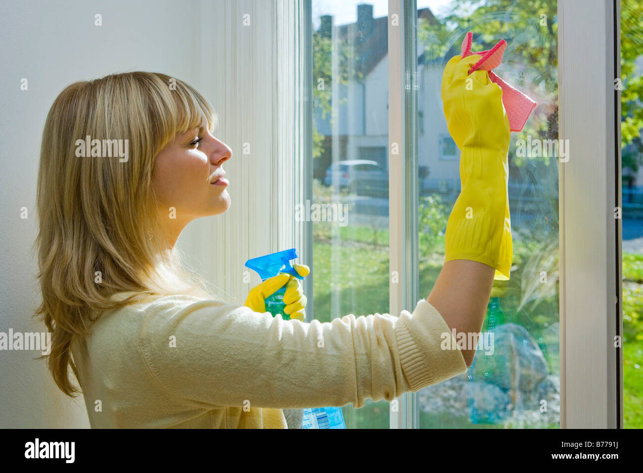 Giovane donna casalinga pulizia di Windows Foto Stock