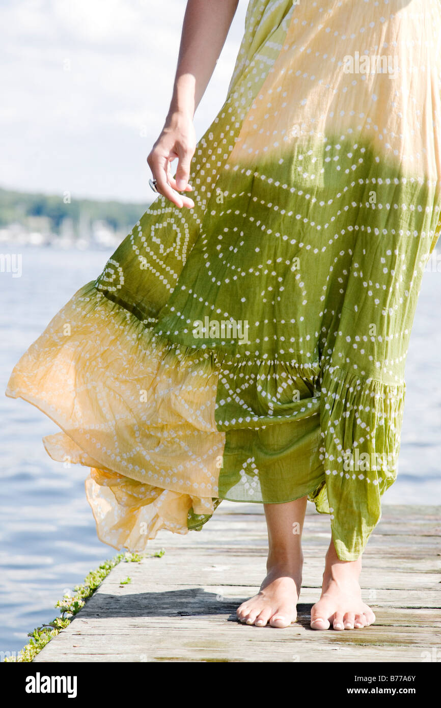 Vento che soffia vestito da donna in piedi sul dock Foto Stock