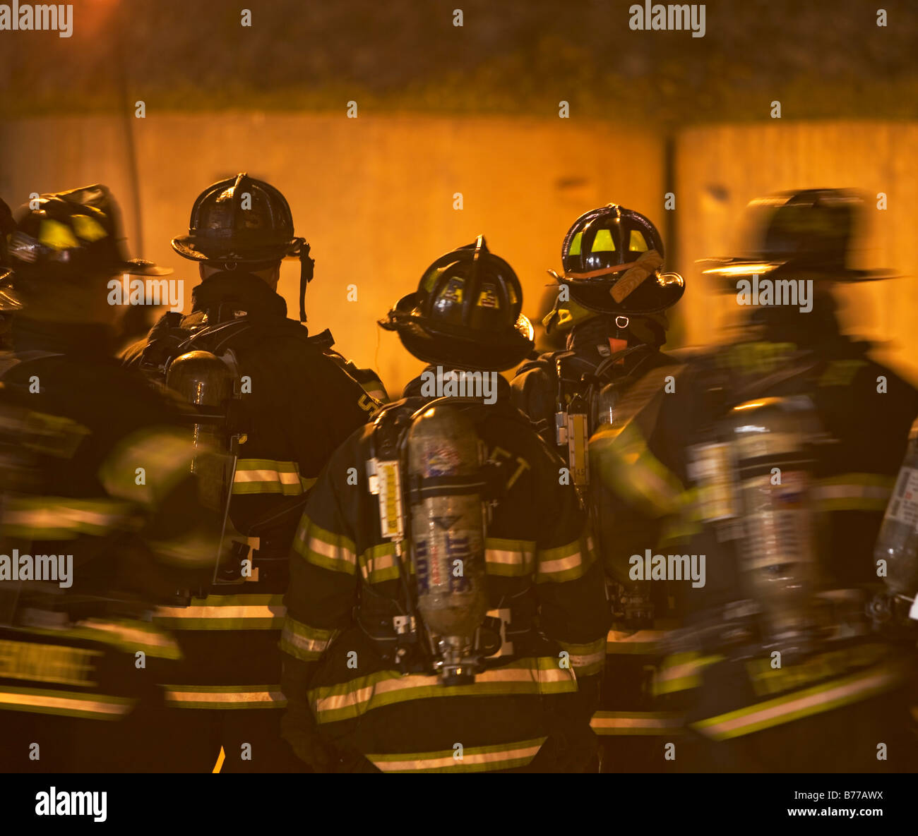 I vigili del fuoco in piedi al di fuori del palazzo in fiamme Foto Stock