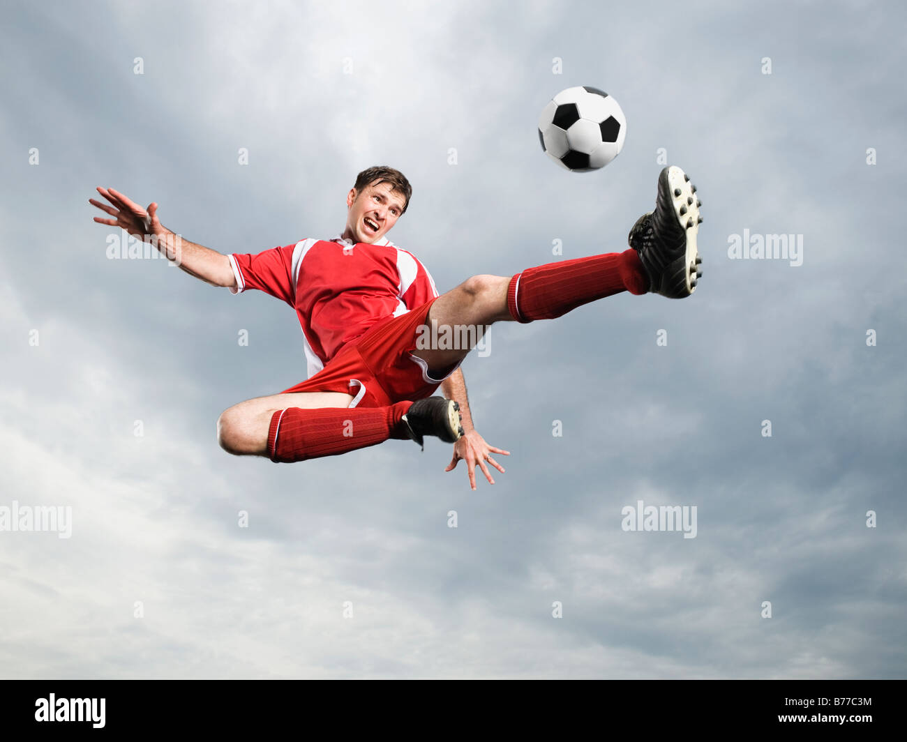 Giocatore di calcio calci palla calcio mid-air Foto Stock