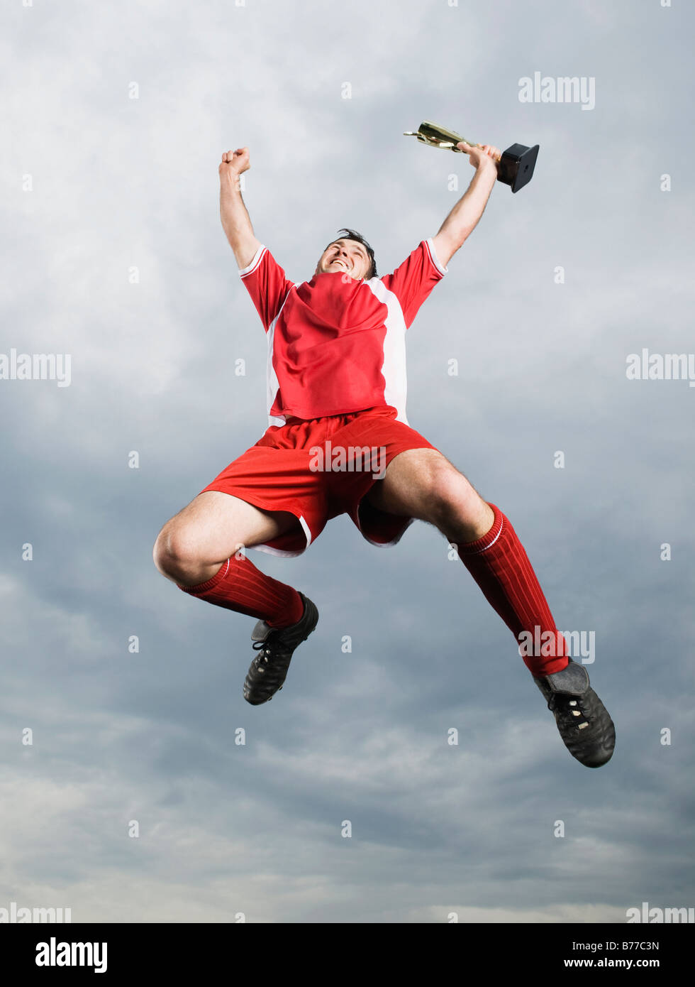 Giocatore di calcio jumping mid-trofeo aria Foto Stock Giocatore di calcio jumping mid-trofeo aria Foto Stock
