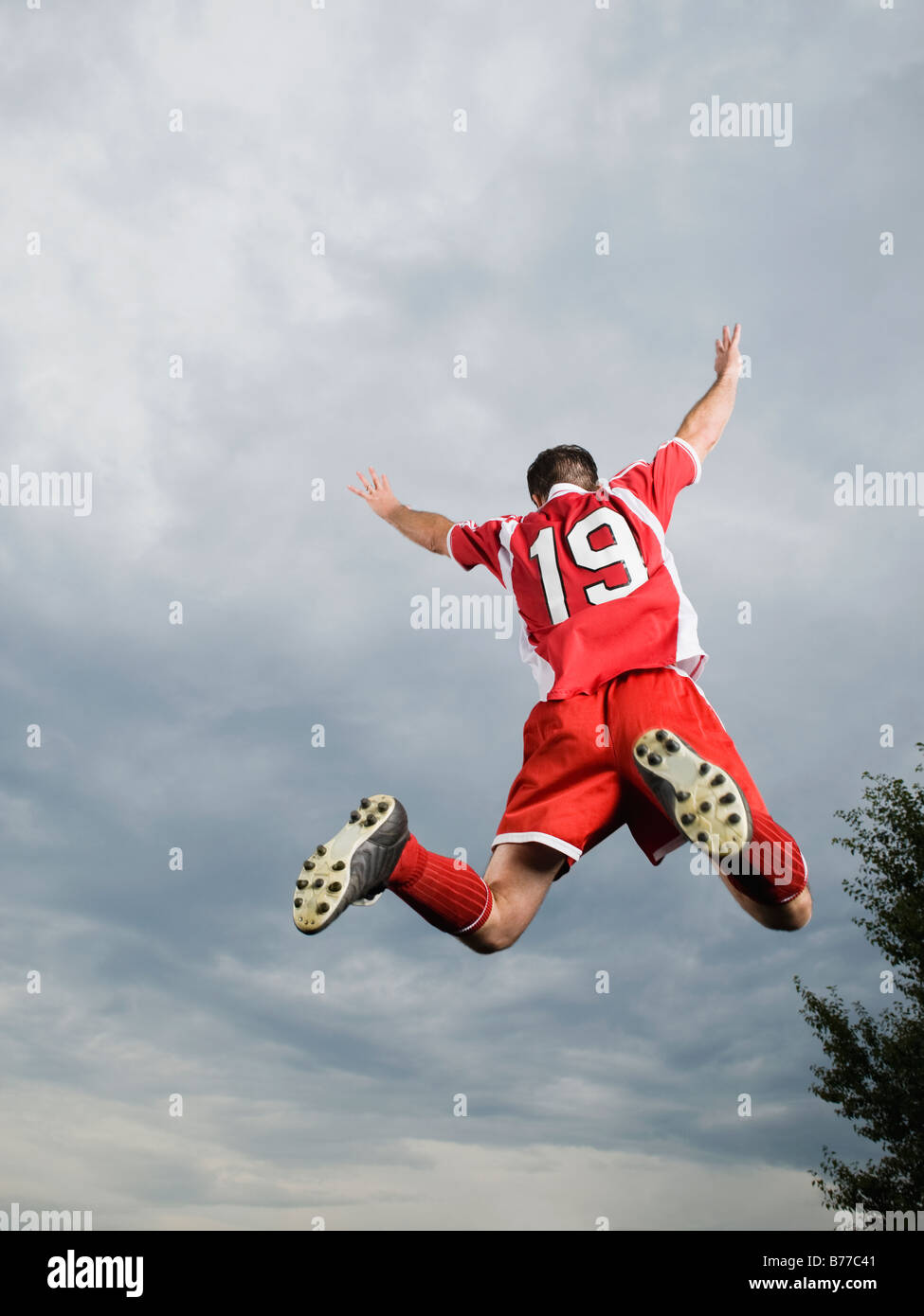 Giocatore di calcio jumping mid-aria a braccia alzate Foto Stock Giocatore di calcio jumping mid-aria a braccia alzate Foto Stock