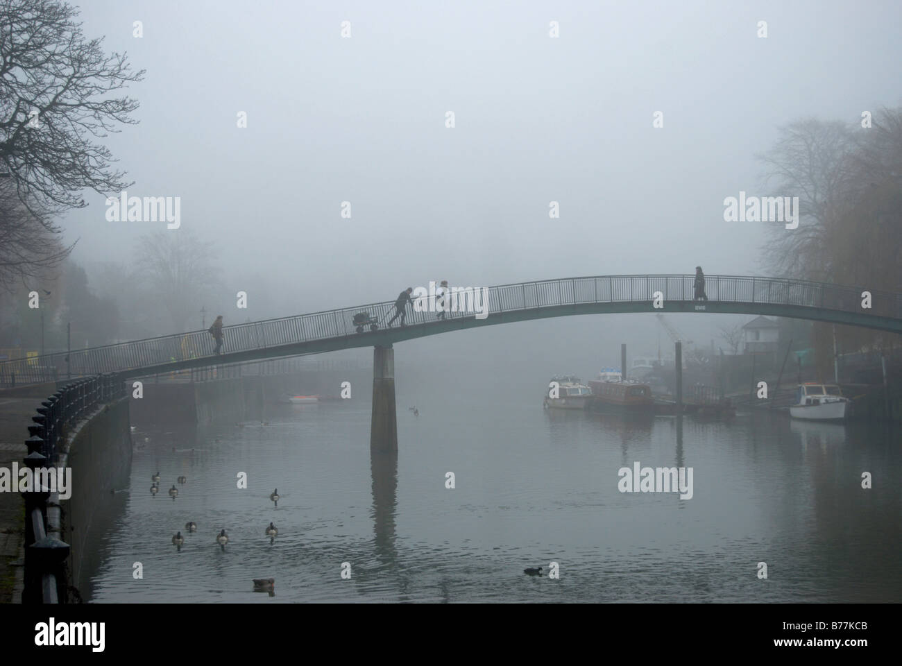 La gente sul ponte pedonale che attraversa il fiume Tamigi tra eel pie island e il Twickenham su un nebbioso giorno Foto Stock