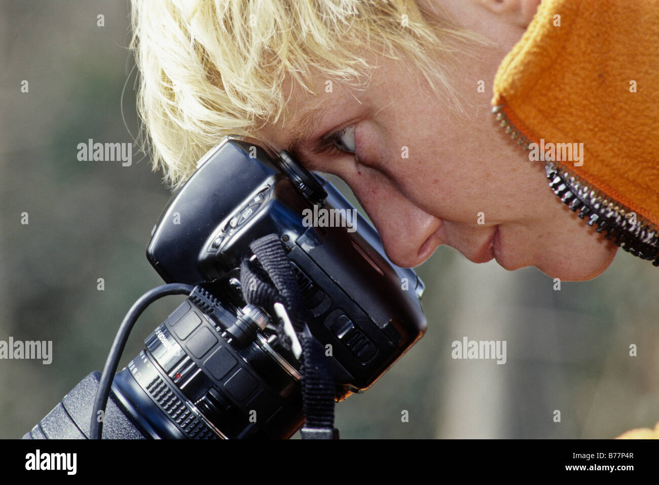 Donna bionda guardando attraverso una fotocamera reflex a obiettivo singolo Foto Stock