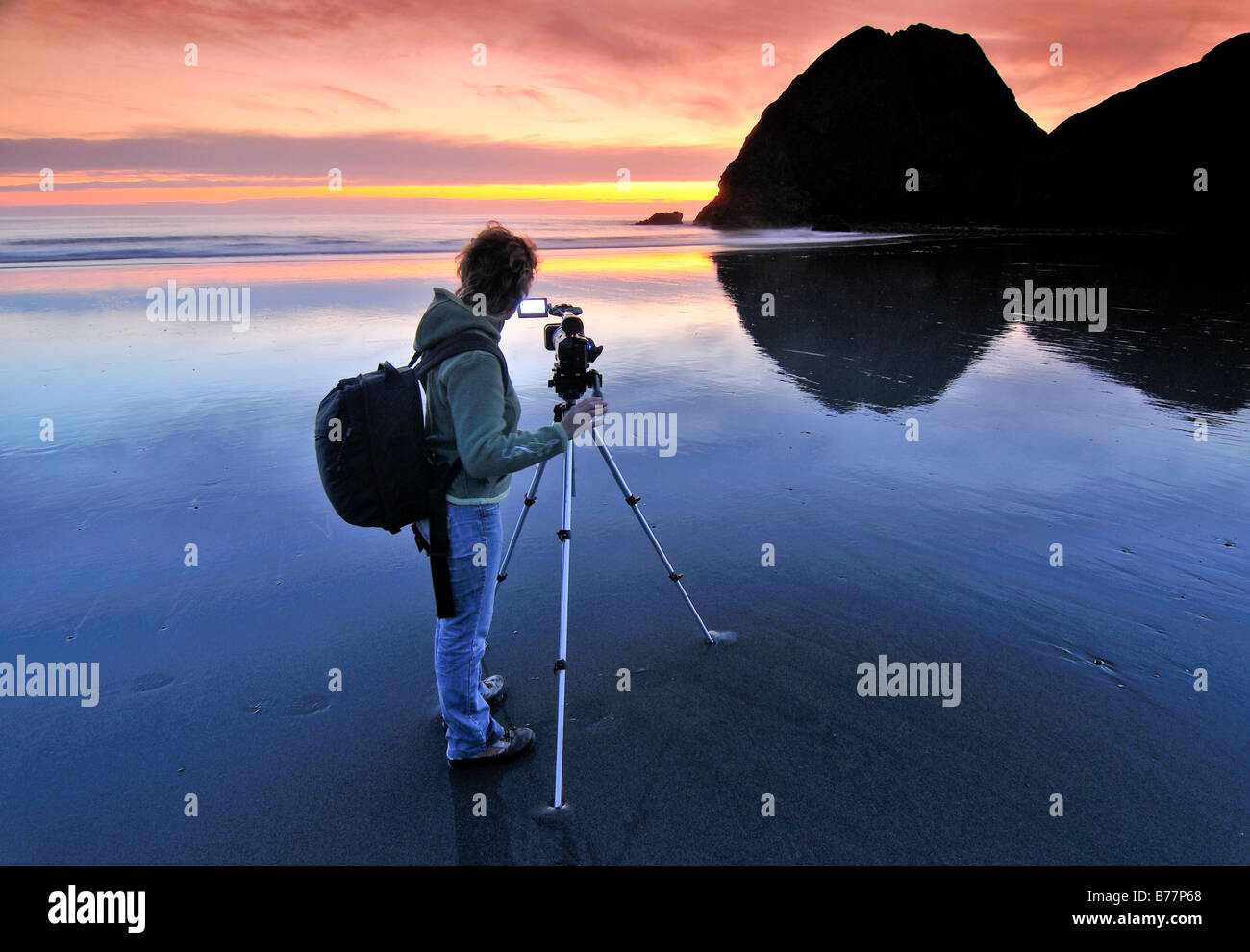 Camerawoman con filmato fotocamera riprese al tramonto con un treppiede a Meyers Creek Beach, pistola River State Park, Oregon Coast, Oregon Foto Stock