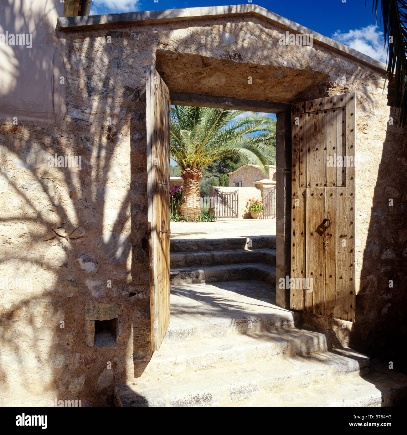 Aperto costellato di legno doppie porte in entrata in pietra del giardino murato in Mallorcan Finca restauro Foto Stock