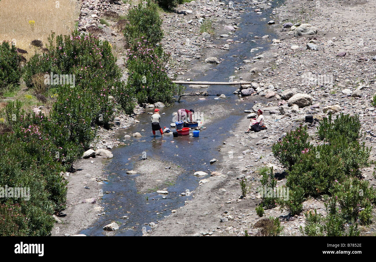 Le donne lavare i vestiti in un flusso in una valle dell'Alto Atlante a sud di Marrakech marocco Foto Stock