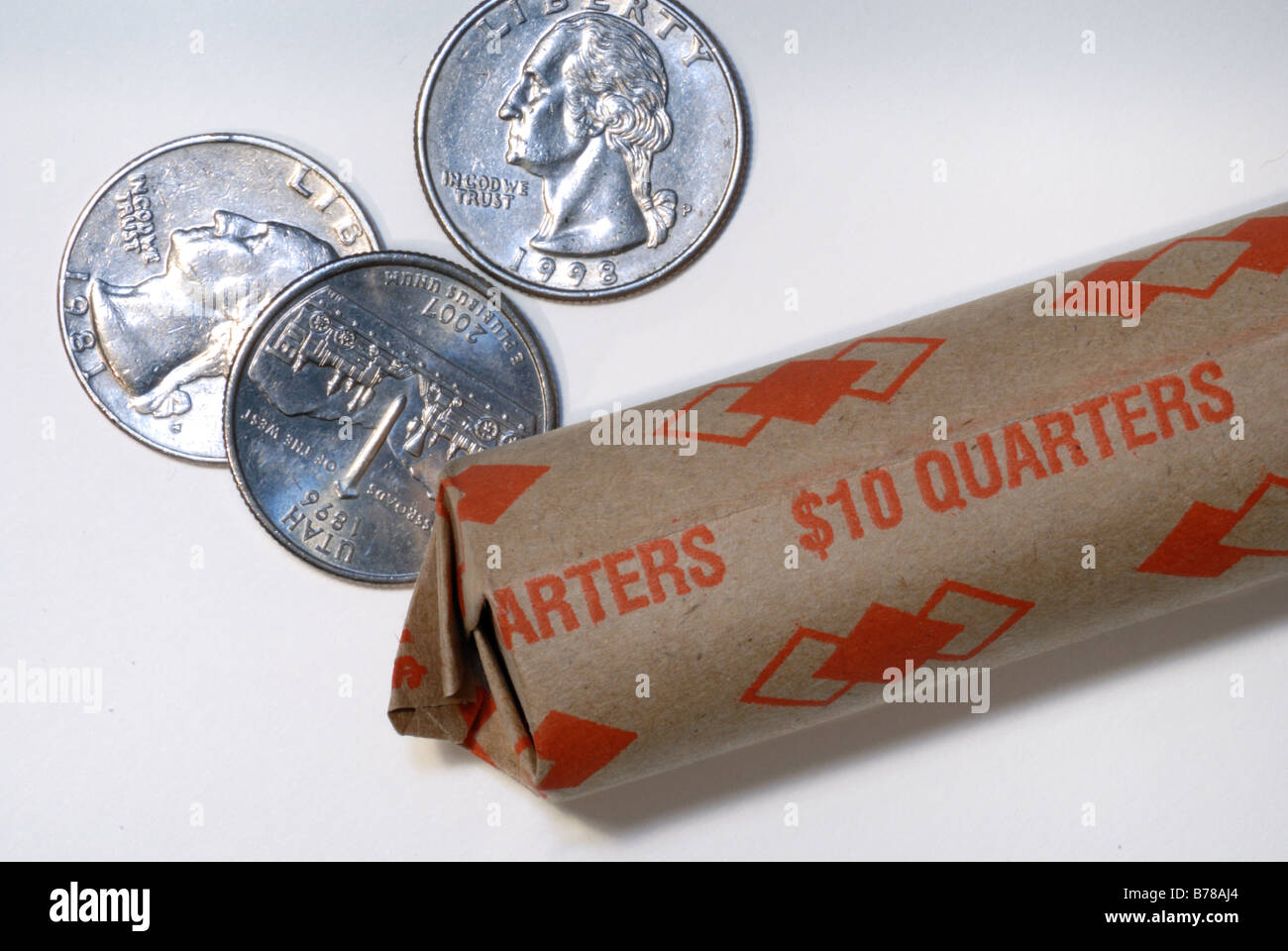 Un $10 rotolo di quarti con alcune monete sparse. Foto Stock