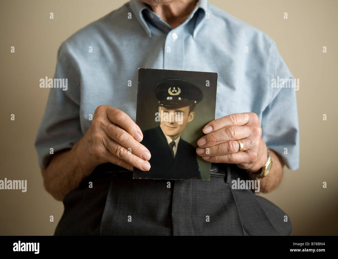 Un anziano veterano trattiene una immagine di se stesso come un ufficiale di marina mercantile durante la Seconda Guerra Mondiale la seconda guerra mondiale Foto Stock