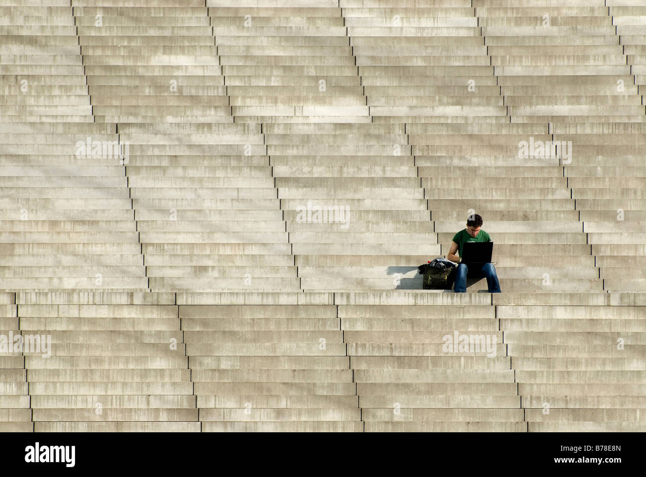 Uomo seduto da solo sulla rampa di scale mentre si lavora su un computer portatile, Berlino, Germania, Europa Foto Stock