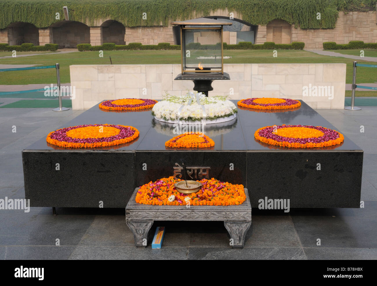 Monumento di pietra, Samādhi, con offerte di fiori a Mohandas Karamchand Gandhi, il Mahatma Gandhi, al Raj Ghat. Delhi, India Foto Stock