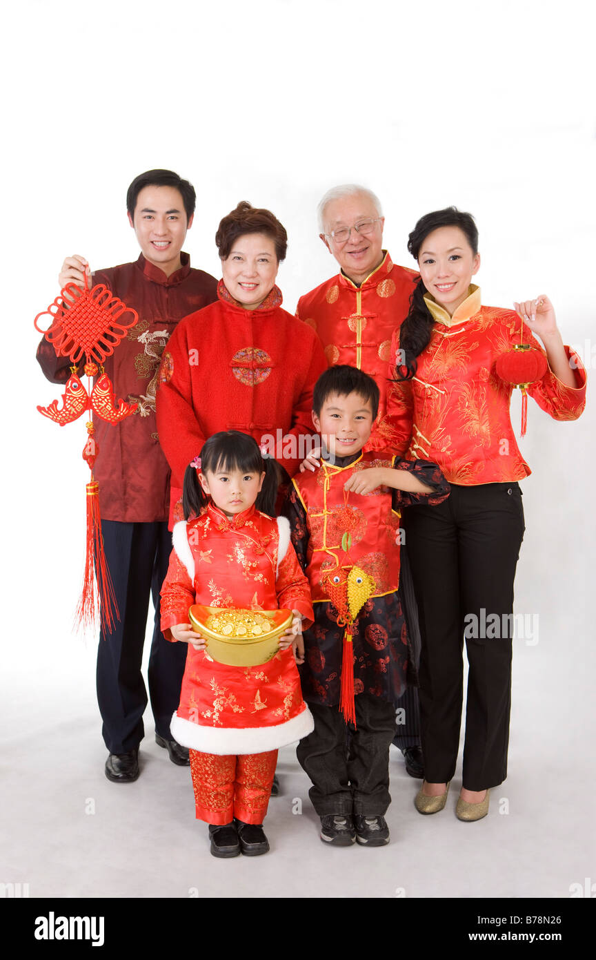I membri della famiglia in abiti tradizionali azienda decorazioni Cinesi e sorridente alla fotocamera Foto Stock