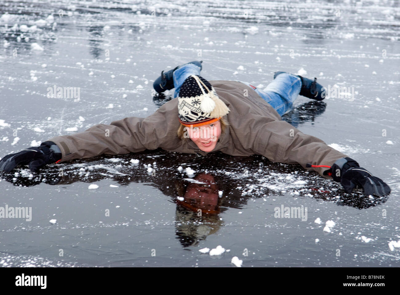 Giovane maschio (16-17) in inverno abiti giacente sul lago ghiacciato, sorridente Foto Stock