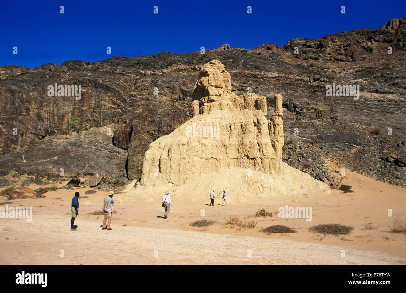 Gruppo di turisti di ispezionare i castelli di argilla che sono naturali insolite formazioni rocciose in la Skeleton Coast. Foto Stock