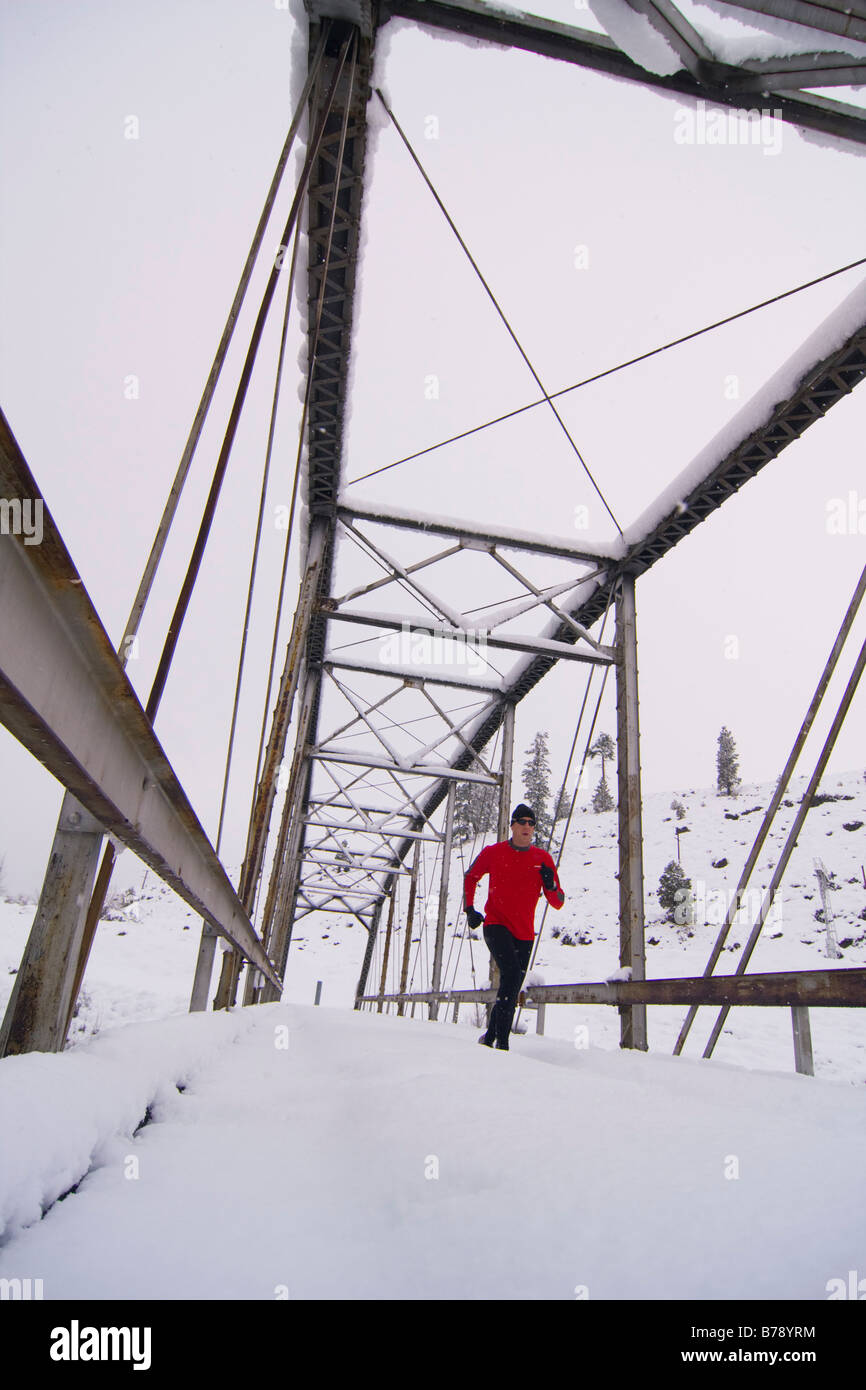 Un uomo che corre attraverso un ponte tressel su un giorno nevoso vicino Truckee in California Foto Stock