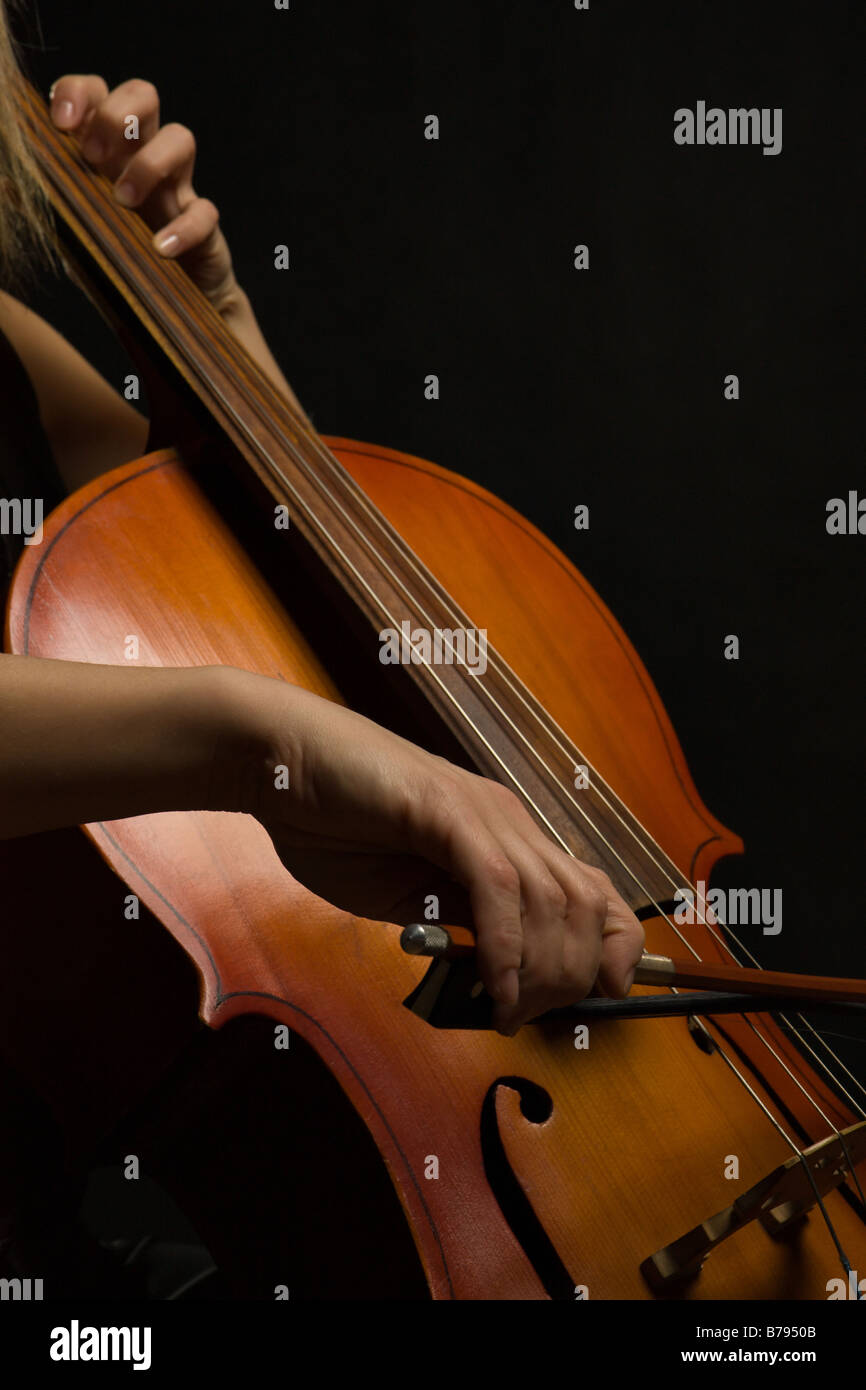 Close up musicista mani con violoncello su sfondo scuro Foto Stock