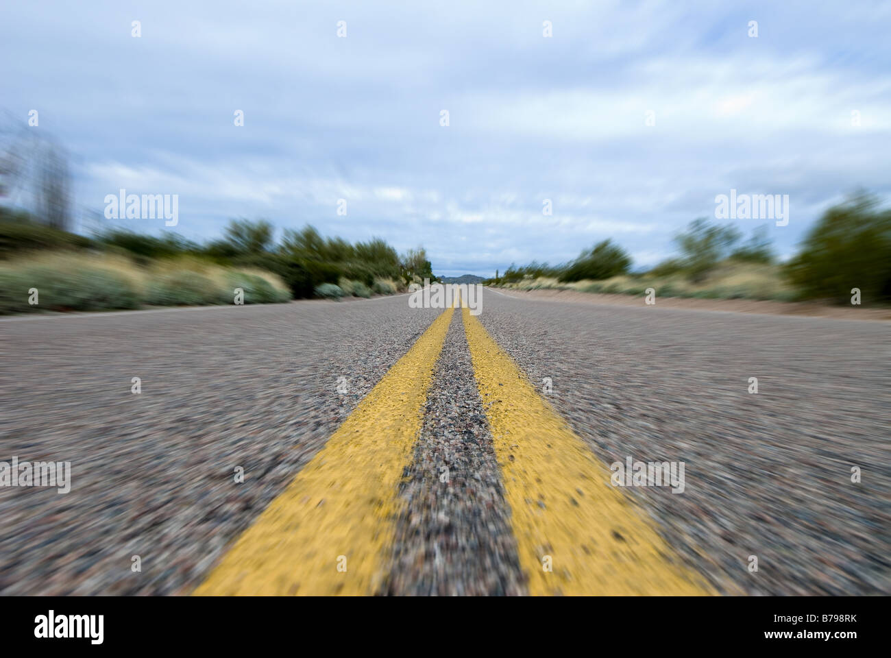 Un solitario strada deserta nel mezzo del deserto di immagine utilizza una sfocatura radiale per fornire l'effetto di movimento Foto Stock