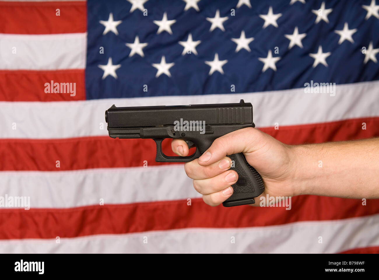 Un uomo mostra la sua semi automatico pistola contro una bandiera americana Foto Stock