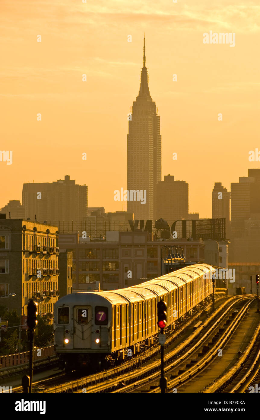 Il numero 7 della metropolitana sopraelevata nella città di Long Island, Queens, a New York City, con l'Empire State Building in background durante il periodo estivo il tramonto. Foto Stock