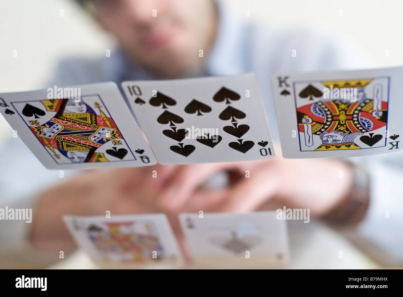 Giovane uomo la distribuzione delle carte in un gioco di poker - sparato da sotto un tavolo di vetro Foto Stock