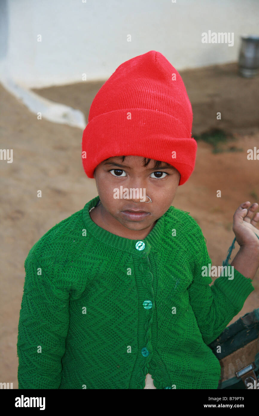 Una giovane ragazza in un verde cardigan e Red Hat al di fuori di casa sua nel villaggio di Mocha, Madhya Pradesh, India Foto Stock