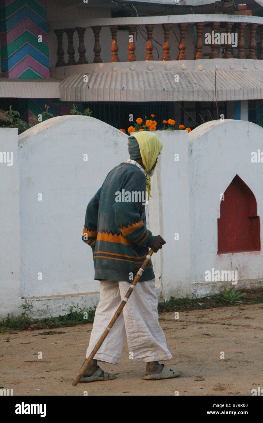 Un uomo anziano con un bastone passeggiando per il Borgo Mocha in Madhya Pradesh, India presto la mattina di Natale Foto Stock