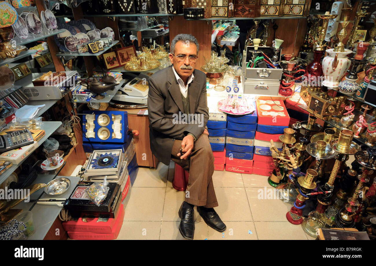 Un negozio turco-keeper si siede nel suo piccolo negozio che vende i beni tradizionali nel Grand Bazaar (Kapali Carsi) ad Istanbul in Turchia. Foto Stock