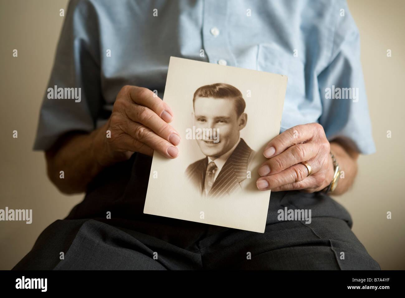 Uomo anziano tenendo una foto di se stesso quando era un giovane uomo Foto Stock