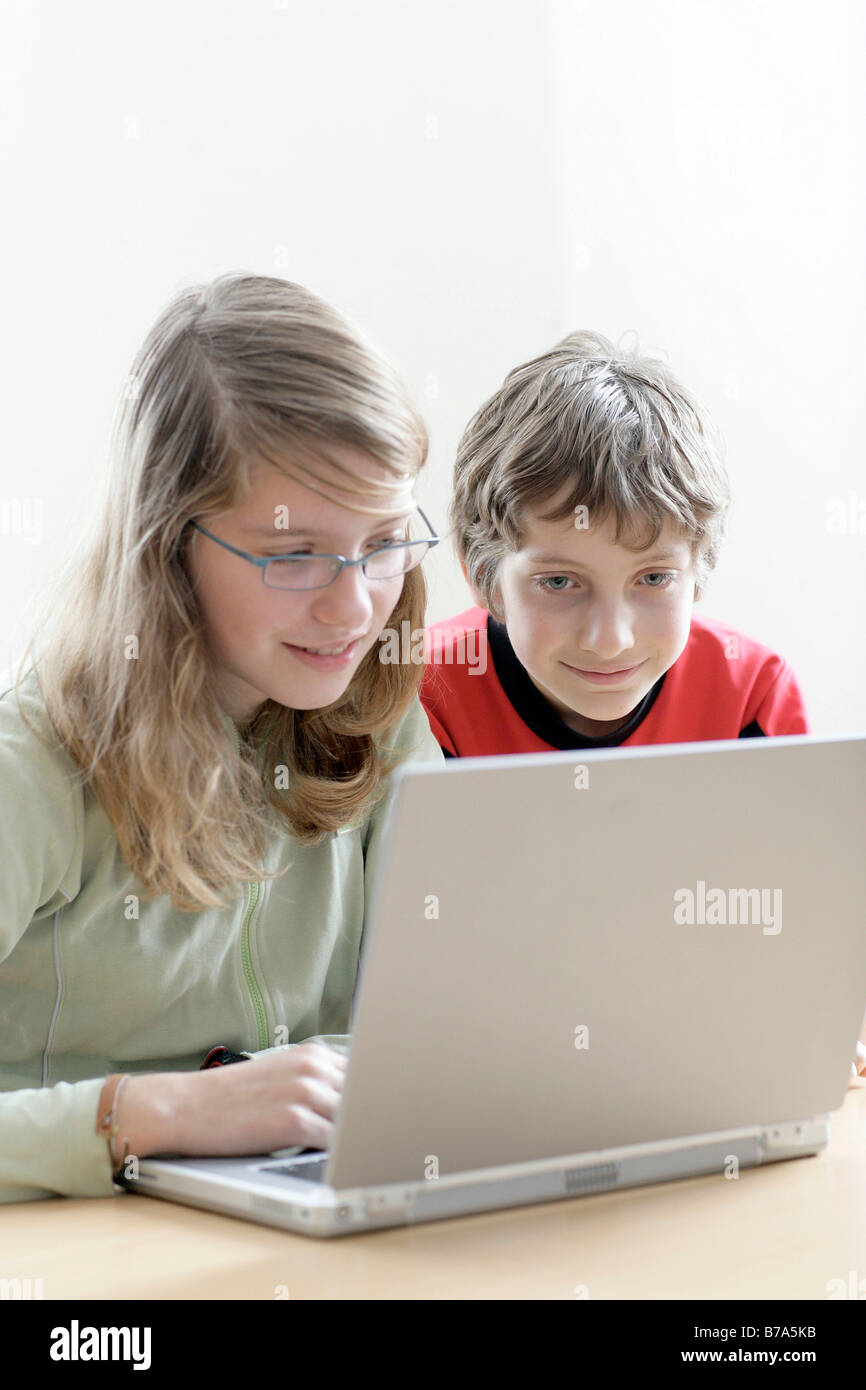 I giovani di 13 anni con la ragazza e il figlio di dieci anni fratello che lavora su un notebook Foto Stock