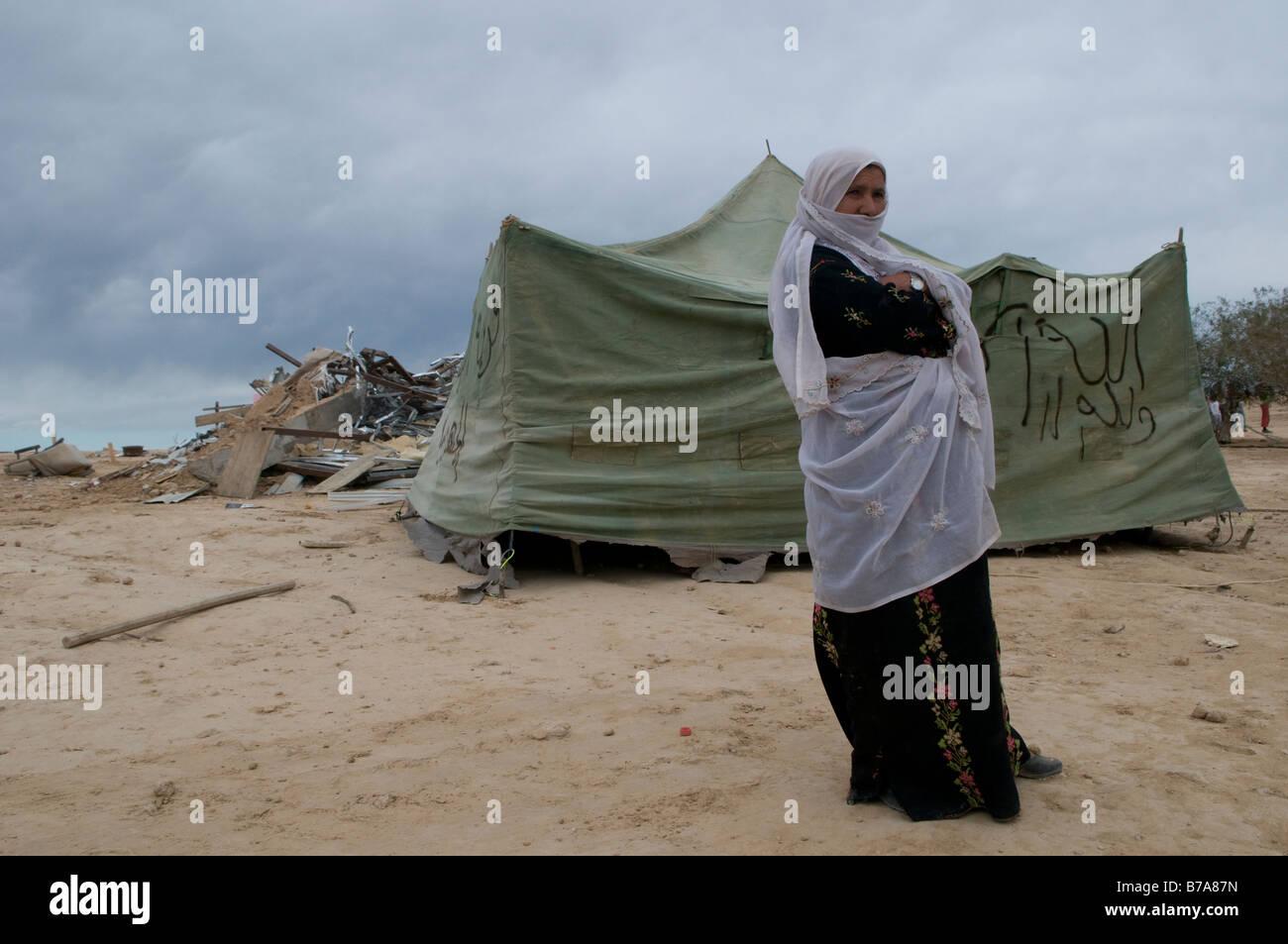 Bedouin donna in mezzo la rovina di case demolite rasa al suolo dalle autorità israeliane in Abdallah Al Atrash sconosciuto villaggio beduino nel deserto del Negev Israele Foto Stock