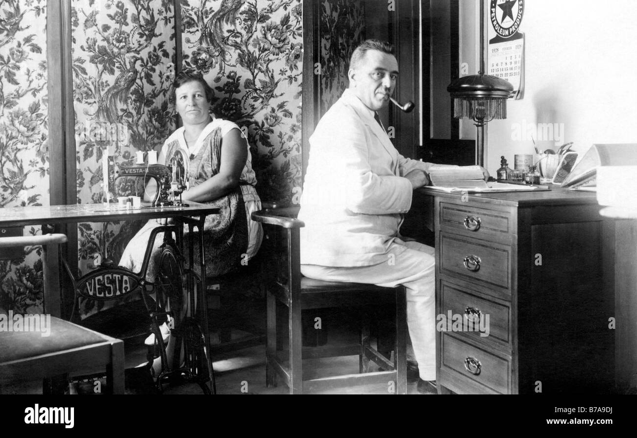 Foto storiche, giovane a casa, l'uomo alla scrivania, la donna con la macchina da cucire, ca. 1920 Foto Stock