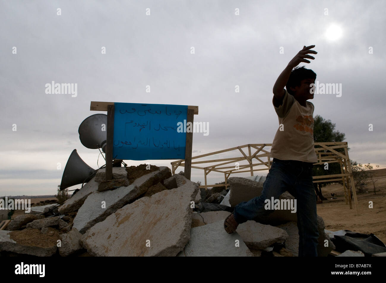 Un giovane ragazzo beduino cammina sopra le rovine di una moschea demolita dalle autorità israeliane in sconosciuto villaggio beduino nel deserto del Negev Israele Foto Stock